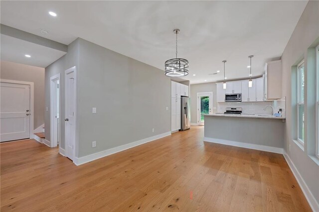 1857 Derrill Dr, Decatur, GA 30032 - kitchen with light countertops, backsplash, appliances with stainless steel finishes, a peninsula, and light wood-style floors