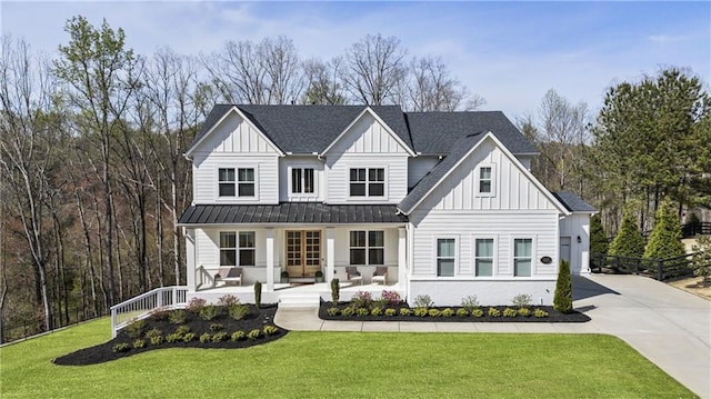 modern inspired farmhouse featuring a porch, concrete driveway, a front yard, board and batten siding, and a standing seam roof