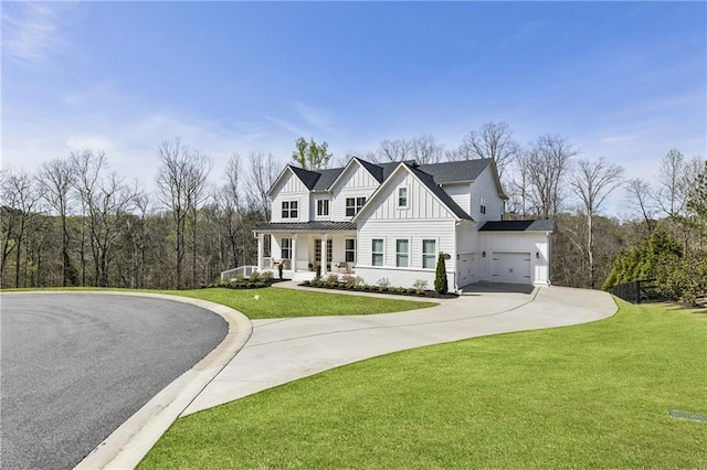 view of front of house with an attached garage, curved driveway, a front lawn, board and batten siding, and a porch