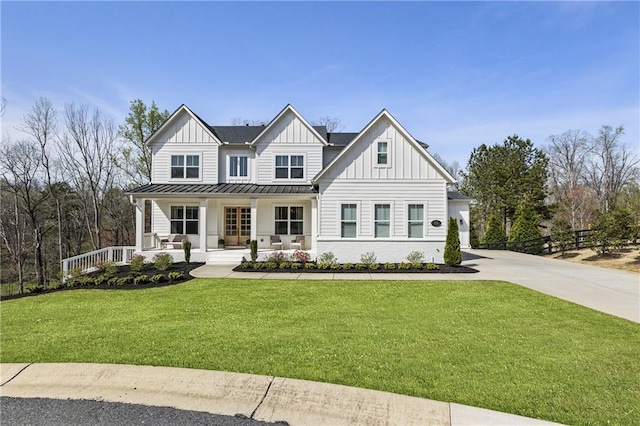 modern farmhouse featuring board and batten siding, a standing seam roof, covered porch, concrete driveway, and a front yard