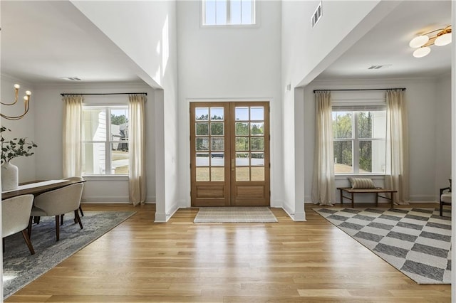 foyer featuring a wealth of natural light, ornamental molding, light wood finished floors, and visible vents