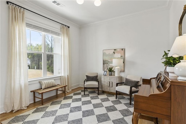 living area featuring baseboards, crown molding, visible vents, and wood finished floors