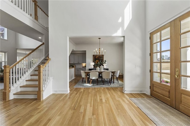 entrance foyer with stairway, plenty of natural light, a high ceiling, baseboards, and light wood-style floors
