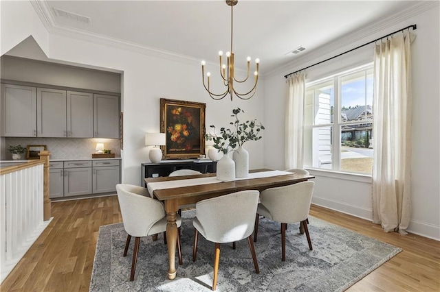 dining space with a chandelier, ornamental molding, and visible vents