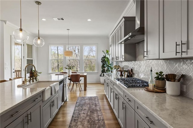 kitchen with a sink, gray cabinets, visible vents, wall chimney exhaust hood, and dark wood-style flooring