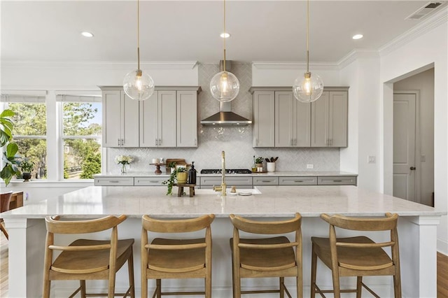 kitchen featuring wall chimney range hood, gray cabinets, a large island, and visible vents