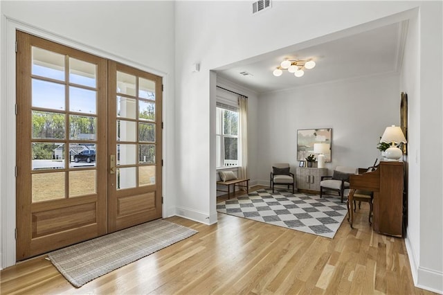 foyer with french doors, ornamental molding, light wood-type flooring, visible vents, and baseboards