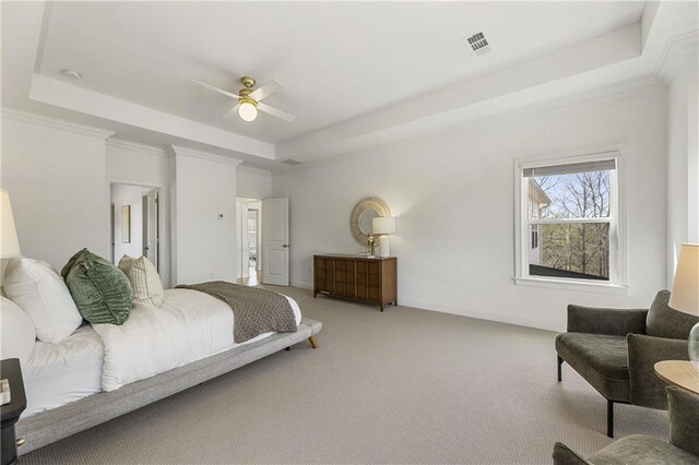 carpeted bedroom featuring crown molding, a raised ceiling, baseboards, and visible vents
