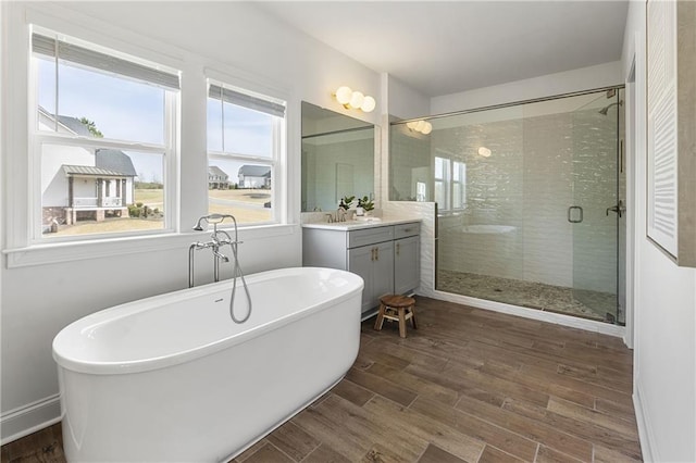 bathroom featuring a shower stall, vanity, a freestanding tub, and wood finished floors