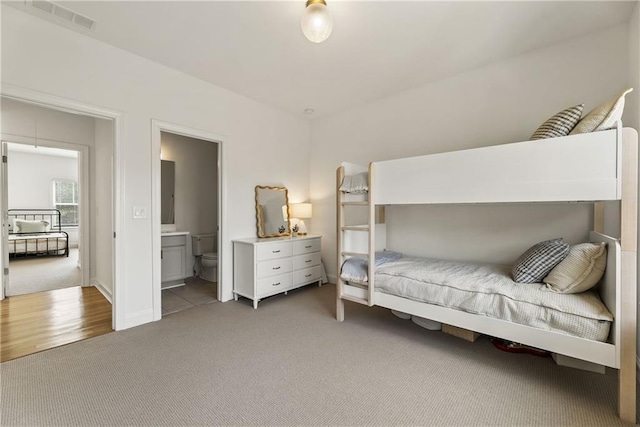 bedroom with carpet, ensuite bath, and visible vents