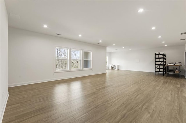 unfurnished living room featuring baseboards, recessed lighting, and wood finished floors