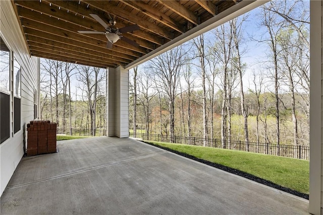 view of patio with a view of trees, a ceiling fan, and a fenced backyard
