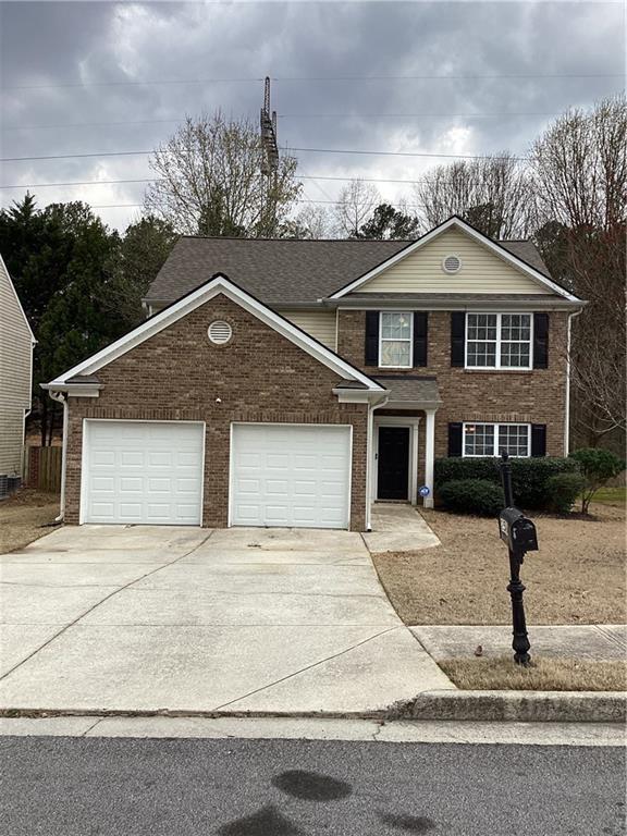 traditional-style home featuring brick siding, driveway, and a garage