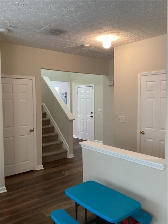 corridor featuring stairway, a textured ceiling, dark wood-type flooring, and baseboards