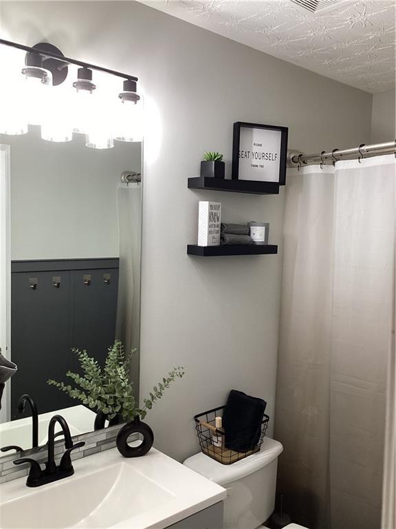 bathroom with toilet, vanity, and a textured ceiling