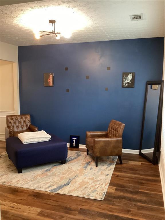 bedroom with visible vents, a textured ceiling, baseboards, and wood finished floors