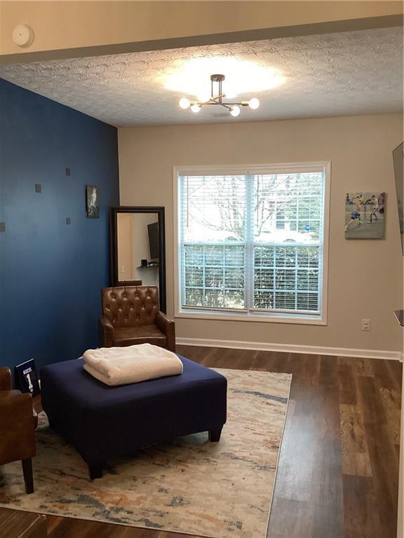 sitting room with baseboards, a textured ceiling, and wood finished floors