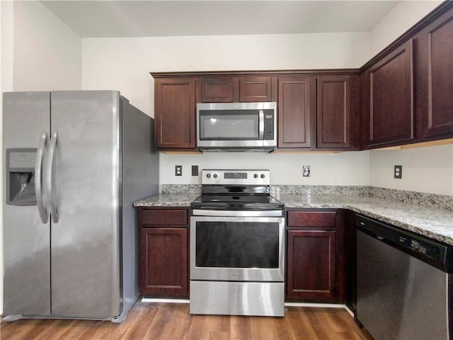 kitchen featuring light hardwood / wood-style flooring, light stone countertops, and appliances with stainless steel finishes