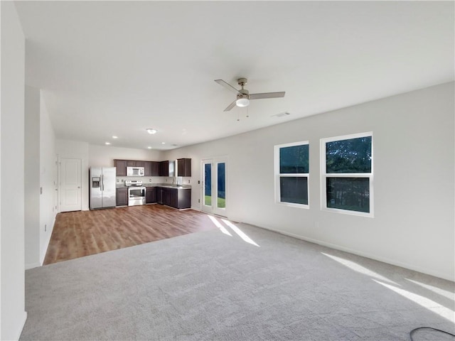 unfurnished living room with visible vents, ceiling fan, light colored carpet, recessed lighting, and a sink