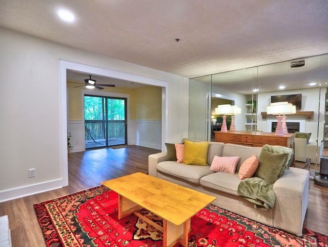 2210 Cumberland Ct SE, Smyrna, GA 30080 - living area featuring wood finished floors, wainscoting, a fireplace, a textured ceiling, and a ceiling fan