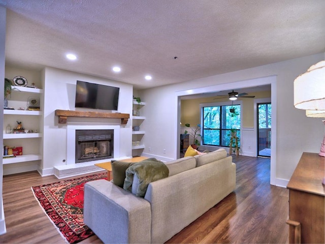 2210 Cumberland Ct SE, Smyrna, GA 30080 - living room with a fireplace with raised hearth, a textured ceiling, baseboards, dark wood-type flooring, and built in features