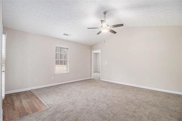 carpeted spare room featuring lofted ceiling, a healthy amount of sunlight, ceiling fan, and baseboards