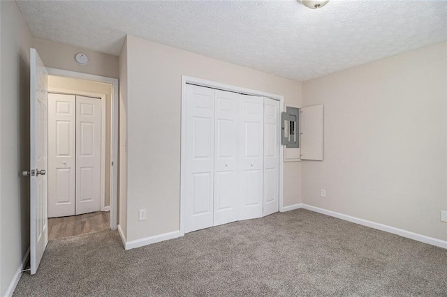 unfurnished bedroom with carpet floors, electric panel, and baseboards