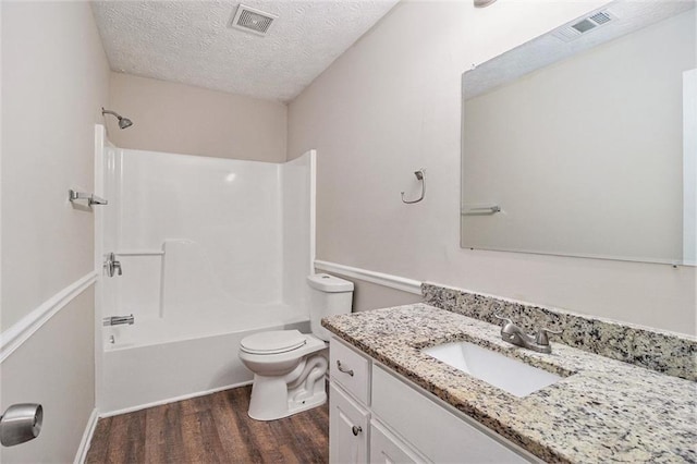 bathroom with visible vents, toilet, vanity, a textured ceiling, and wood finished floors