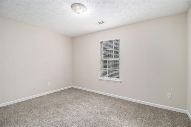 empty room with carpet floors, visible vents, baseboards, and a textured ceiling