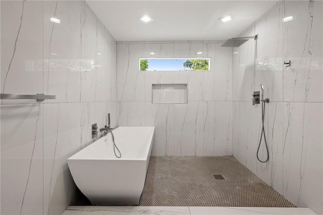 bathroom with shower with separate bathtub and tile walls