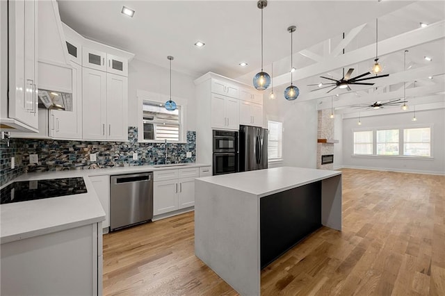 kitchen with hanging light fixtures, backsplash, a center island, white cabinetry, and appliances with stainless steel finishes