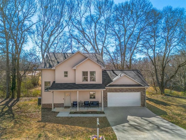 traditional home with a garage, concrete driveway, covered porch, and a front lawn