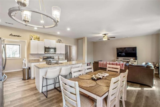 dining room with recessed lighting, ceiling fan with notable chandelier, visible vents, baseboards, and light wood-style floors