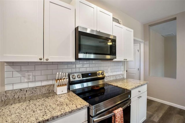 kitchen featuring stainless steel appliances, light stone countertops, white cabinets, and tasteful backsplash