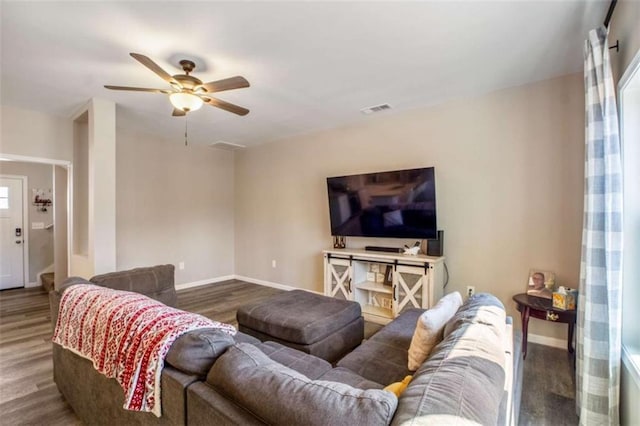 living room featuring a ceiling fan, wood finished floors, visible vents, and baseboards