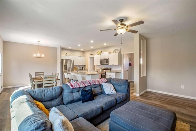 living room featuring recessed lighting, baseboards, wood finished floors, and ceiling fan with notable chandelier