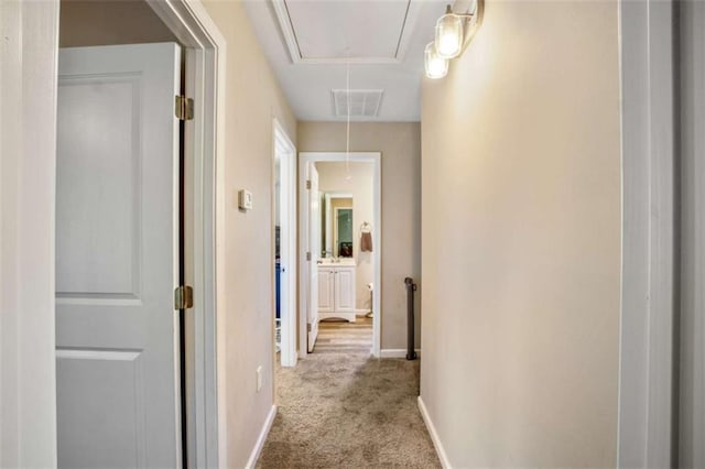 hall with visible vents, carpet floors, attic access, and baseboards