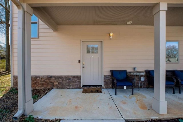 entrance to property featuring stone siding and a patio area