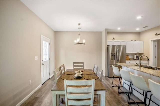 dining space with a chandelier, recessed lighting, dark wood finished floors, and baseboards