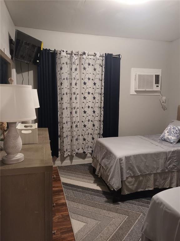 bedroom with a wall mounted AC and dark hardwood / wood-style floors