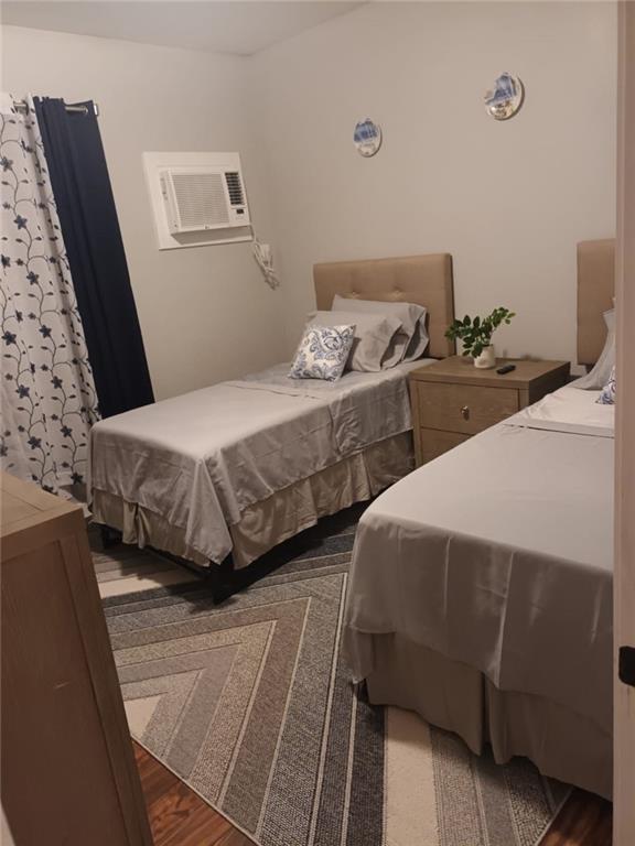 bedroom featuring a wall mounted AC and dark wood-type flooring