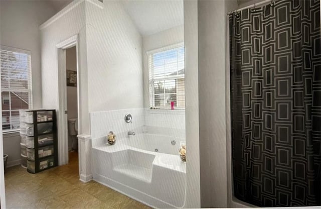 bathroom with toilet, a tub, and vaulted ceiling