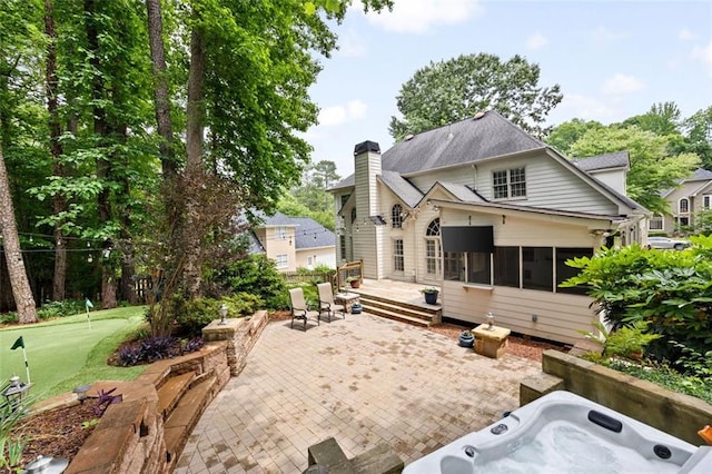 10000 Groomsbridge Rd, Johns Creek, GA 30022 - back of property with an area to practice putting, a patio area, an outdoor hot tub, a chimney, and a sunroom