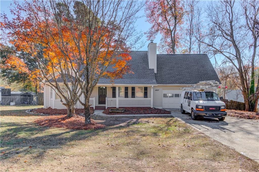 cape cod home featuring covered porch, a garage, and a front yard