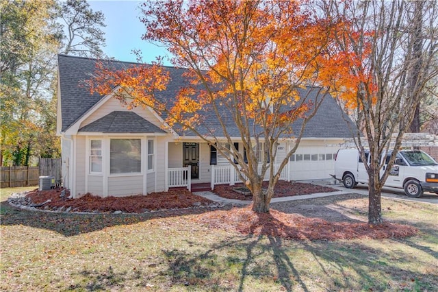 view of front of home featuring covered porch, a garage, central air condition unit, and a front yard