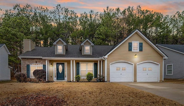 new england style home with a shingled roof, concrete driveway, and an attached garage