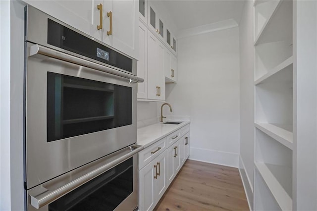 3903 Indian Shoals Rd SE, Bethlehem, GA 30620 - kitchen featuring stainless steel double oven, light wood-style flooring, white cabinets, and glass insert cabinets