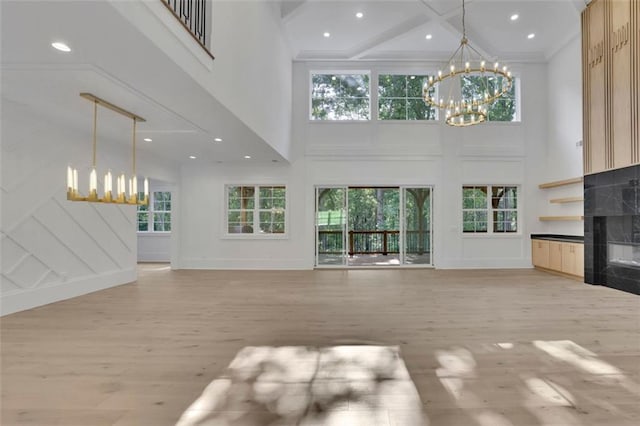3903 Indian Shoals Rd SE, Bethlehem, GA 30620 - unfurnished living room with a chandelier, a high ceiling, a premium fireplace, a decorative wall, and light wood-style floors