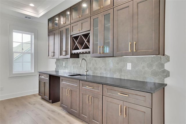 3903 Indian Shoals Rd SE, Bethlehem, GA 30620 - kitchen with light wood-style flooring, decorative backsplash, dark countertops, recessed lighting, and glass insert cabinets