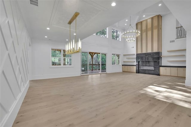 3903 Indian Shoals Rd SE, Bethlehem, GA 30620 - unfurnished living room featuring a chandelier, a decorative wall, healthy amount of natural light, light wood-style flooring, and a towering ceiling
